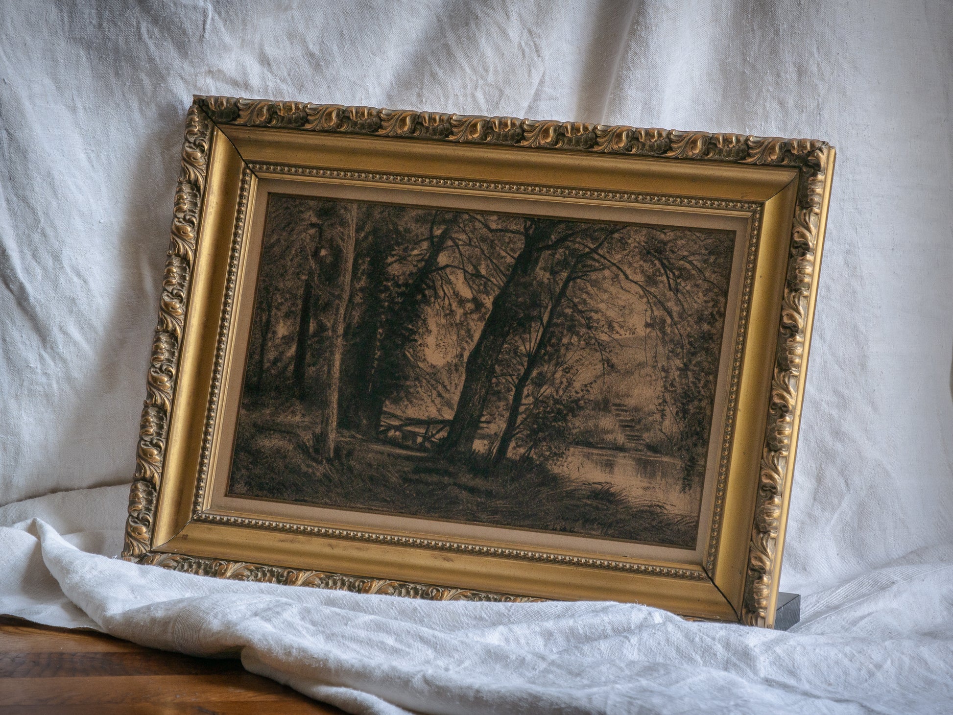 Framed artwork of a forest scene on a white fabric background