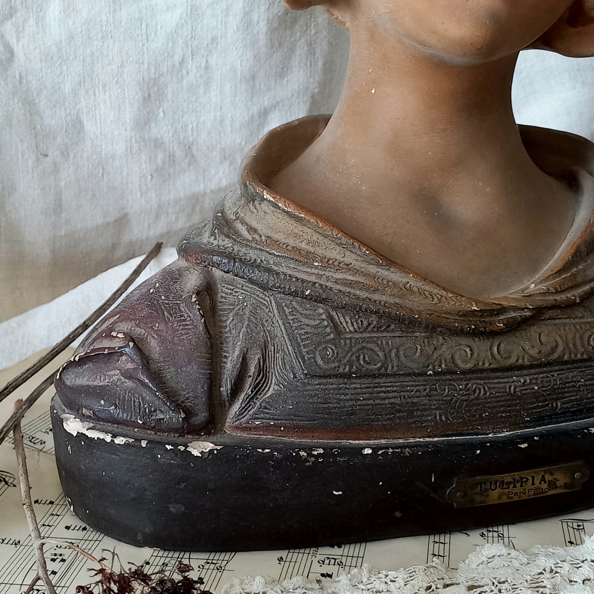 Antique bust of a woman wearing a bonnet on a white fabric background