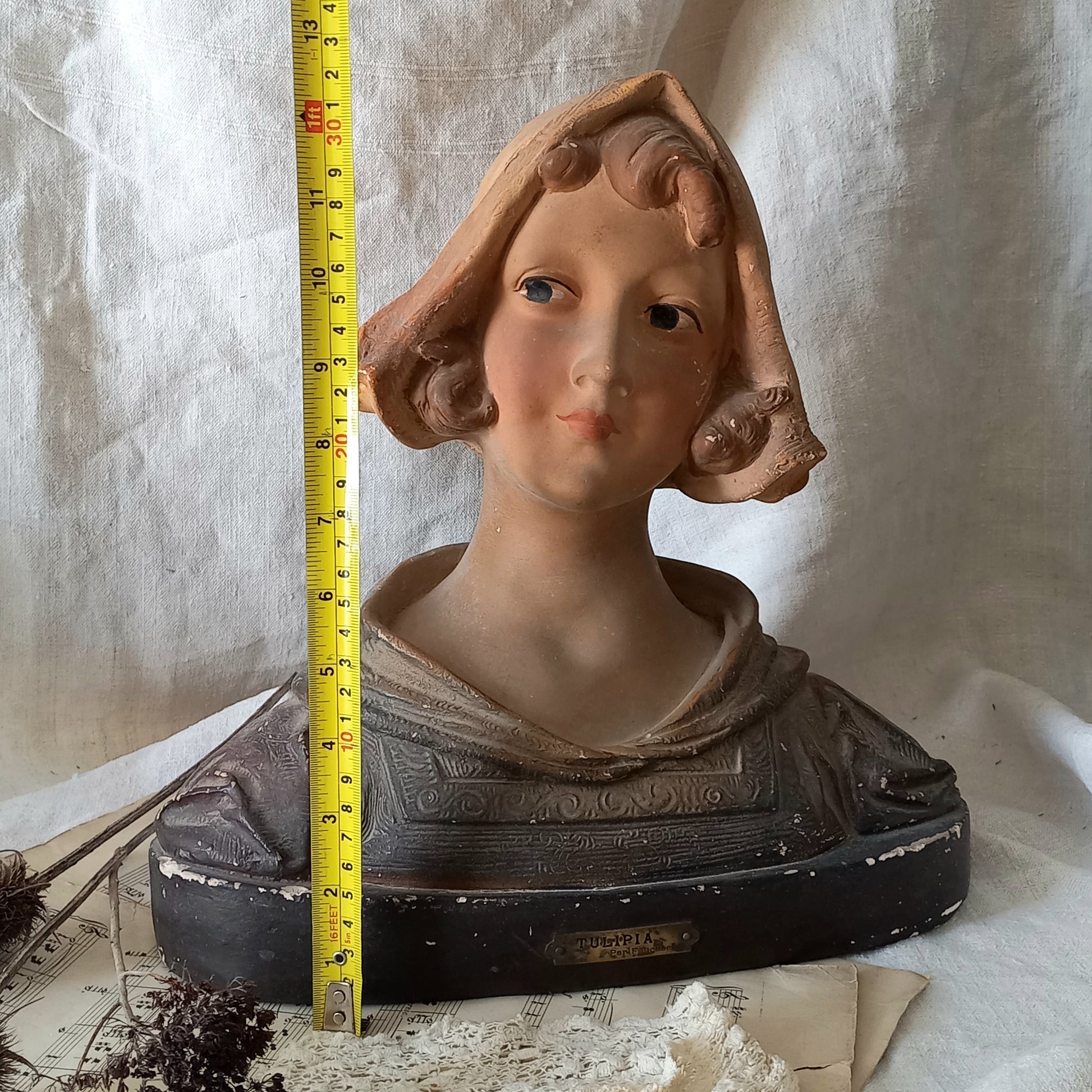 Antique bust of a woman wearing a bonnet on a white fabric background