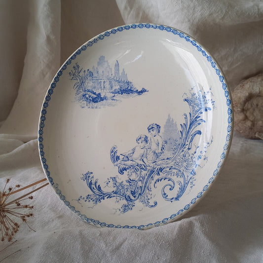 An attractive French antique footed ironstone cake plate with a blue transfer pattern depicting architecture, cherubs, and flowers; a very pretty and delicate pattern.
Original antique ironstone pieces of this age and condition are becoming increasingly difficult to source to this a rare treat to discover.