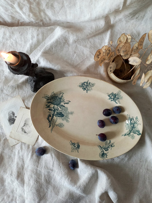 French antique oval ironstone serving plate with teal colour sunflower transferware pattern that over many decades has become a pleasing, warm shade of creamy white with crazing and tea-staining.