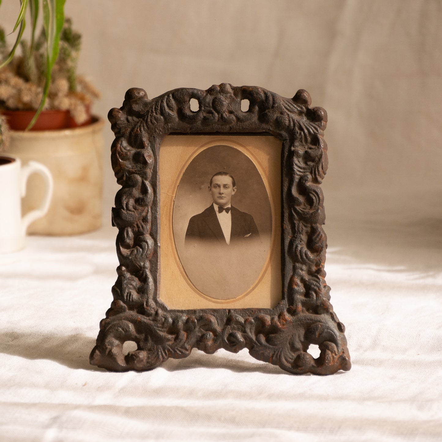 A small French antique decorative cast iron photo frame - a very interesting artisan-made table-top frame with wonderful time-worn patina. There is a glass front and a hardboard backing board. The photo of the gentleman in a tuxedo is an original French period photo that we have placed inside for display purposes and is included in the sale.