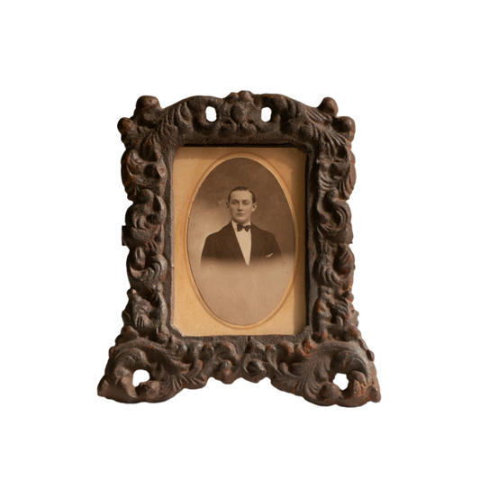 A small French antique decorative cast iron photo frame - a very interesting artisan-made table-top frame with wonderful time-worn patina. There is a glass front and a hardboard backing board. The photo of the gentleman in a tuxedo is an original French period photo that we have placed inside for display purposes and is included in the sale.