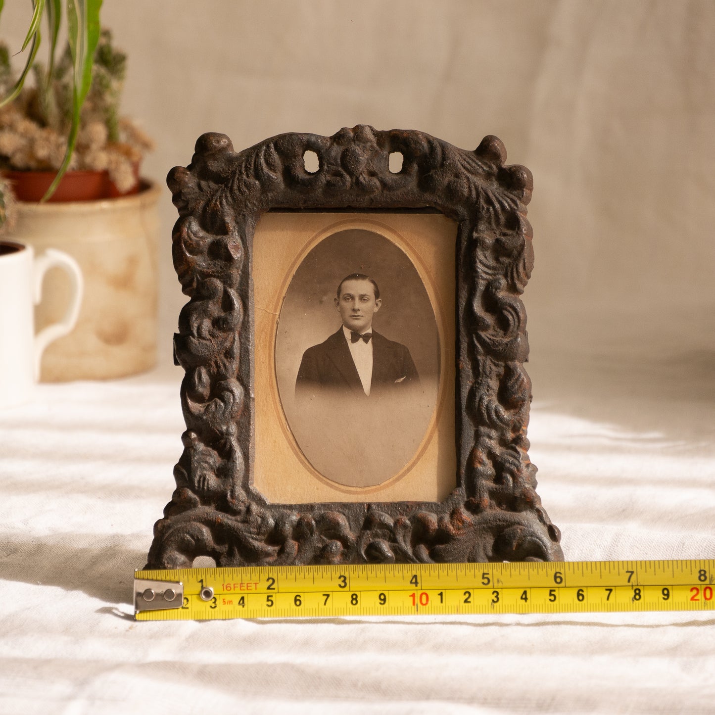 A small French antique decorative cast iron photo frame - a very interesting artisan-made table-top frame with wonderful time-worn patina. There is a glass front and a hardboard backing board. The photo of the gentleman in a tuxedo is an original French period photo that we have placed inside for display purposes and is included in the sale.