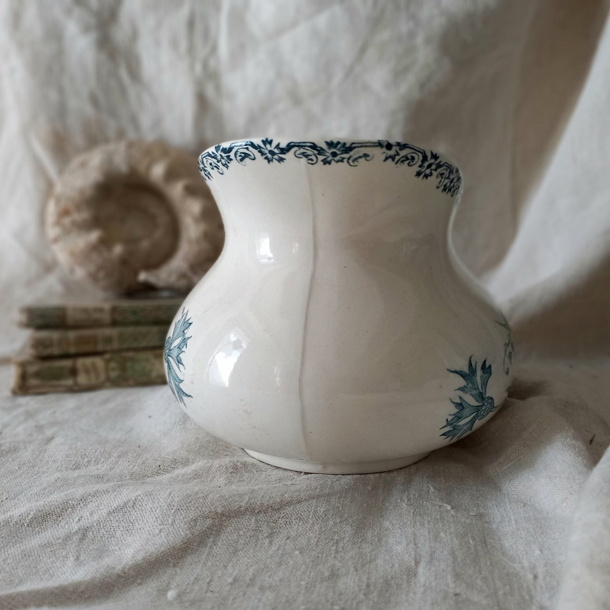 White ceramic vase with teal patterns on a textured surface