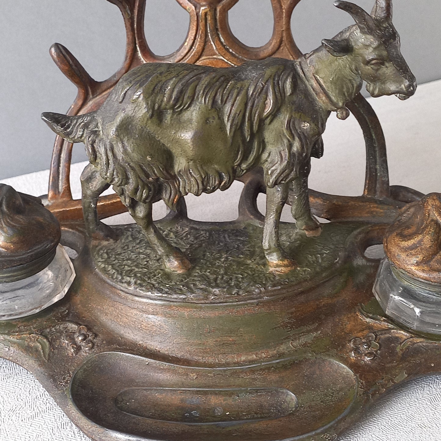 A stunning French art nouveau double inkwell with a goat figurine.
This wonderful antique inkwell has been sculpted in metal and signed by the artist (see photos). Behind the beautiful goat figurine are two pen rests and either side of the goat are two small glass ink pots with decorative metal lids.
The metal is finished in a lovely shade of green that has worn over time with traces of gold colour beneath - it has a wonderful patina of time all over it.