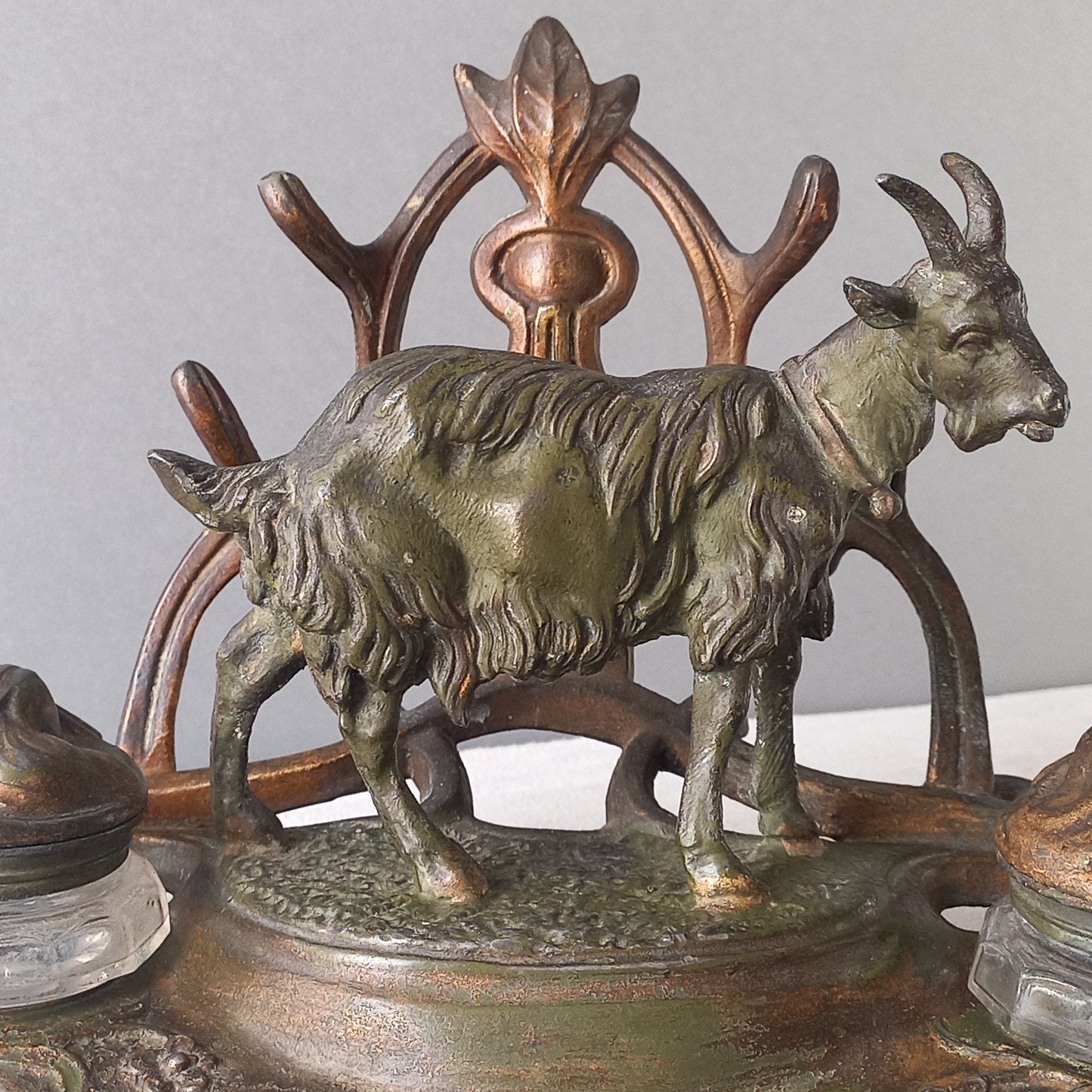 A stunning French art nouveau double inkwell with a goat figurine.
This wonderful antique inkwell has been sculpted in metal and signed by the artist (see photos). Behind the beautiful goat figurine are two pen rests and either side of the goat are two small glass ink pots with decorative metal lids.
The metal is finished in a lovely shade of green that has worn over time with traces of gold colour beneath - it has a wonderful patina of time all over it.