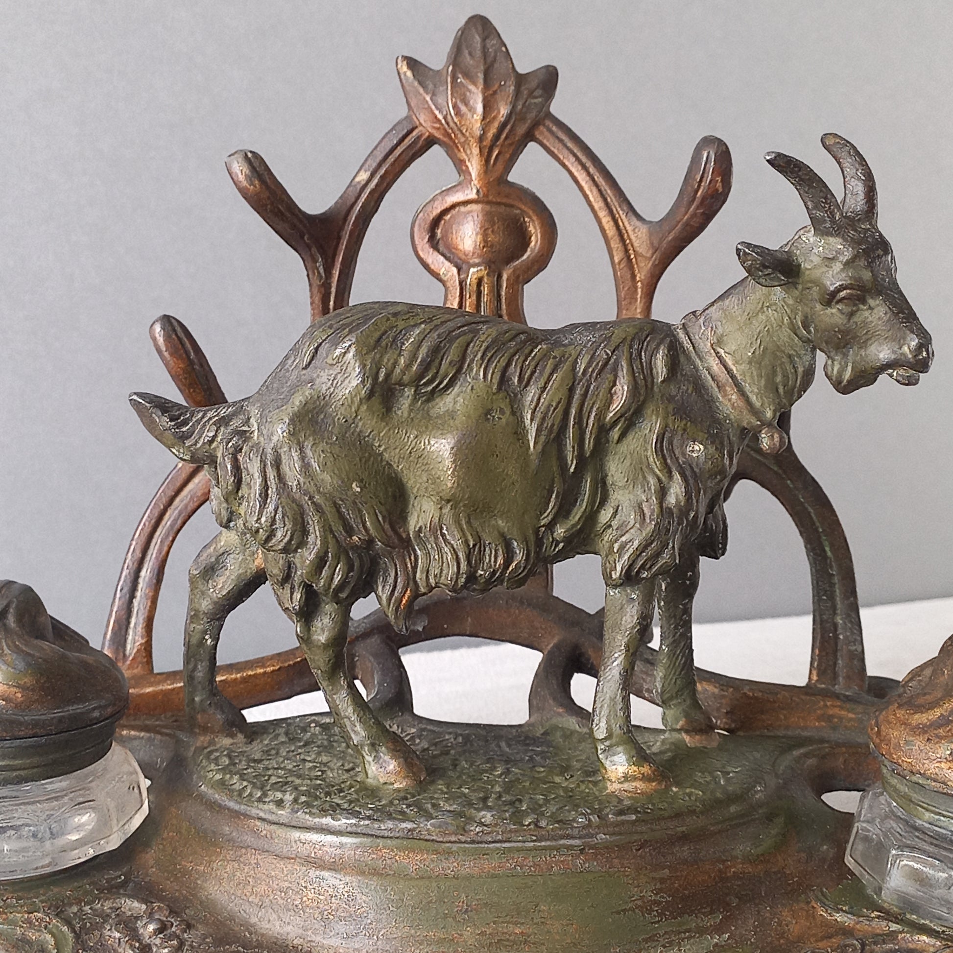 A stunning French art nouveau double inkwell with a goat figurine.
This wonderful antique inkwell has been sculpted in metal and signed by the artist (see photos). Behind the beautiful goat figurine are two pen rests and either side of the goat are two small glass ink pots with decorative metal lids.
The metal is finished in a lovely shade of green that has worn over time with traces of gold colour beneath - it has a wonderful patina of time all over it.