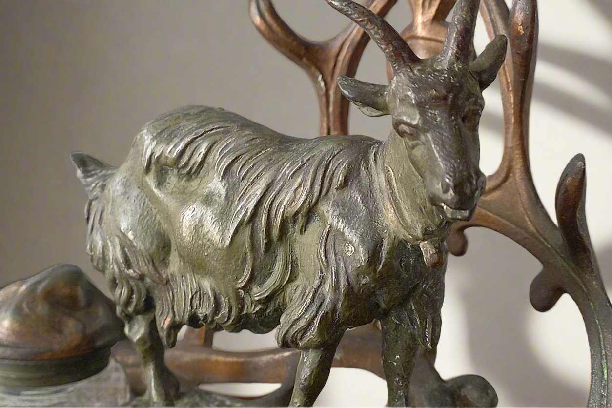 A stunning French art nouveau double inkwell with a goat figurine.
This wonderful antique inkwell has been sculpted in metal and signed by the artist (see photos). Behind the beautiful goat figurine are two pen rests and either side of the goat are two small glass ink pots with decorative metal lids.
The metal is finished in a lovely shade of green that has worn over time with traces of gold colour beneath - it has a wonderful patina of time all over it.