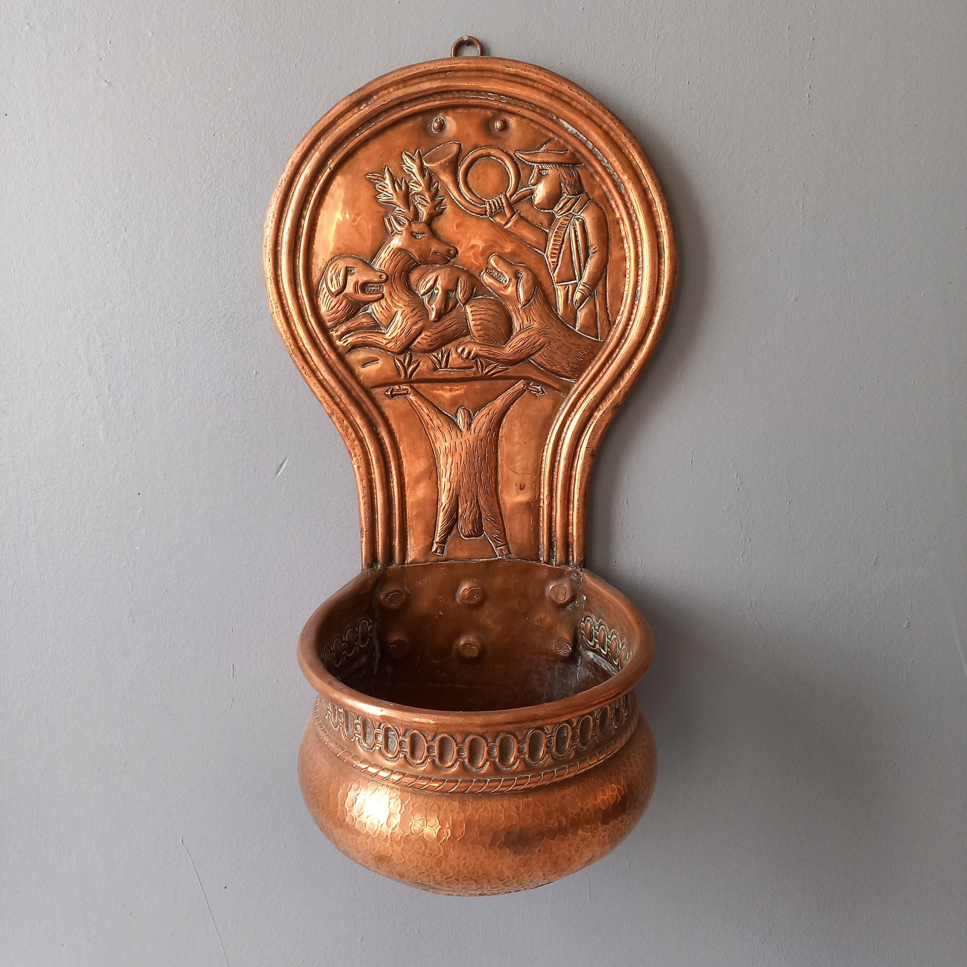 A very handsome copper vintage/antique wall-mounted planter with a hunting scene that I purchased in south west France.
This wonderful rustic piece may at some time have had another purpose, although being a planter seems to suit it just perfectly. There is a hanging hook to the rear, although it can also be displayed sitting on a flat surface as it's depicted in my photos - it's very interesting that we can also see the crude yet charming way this heavy copper planter was constructed by the artisan.