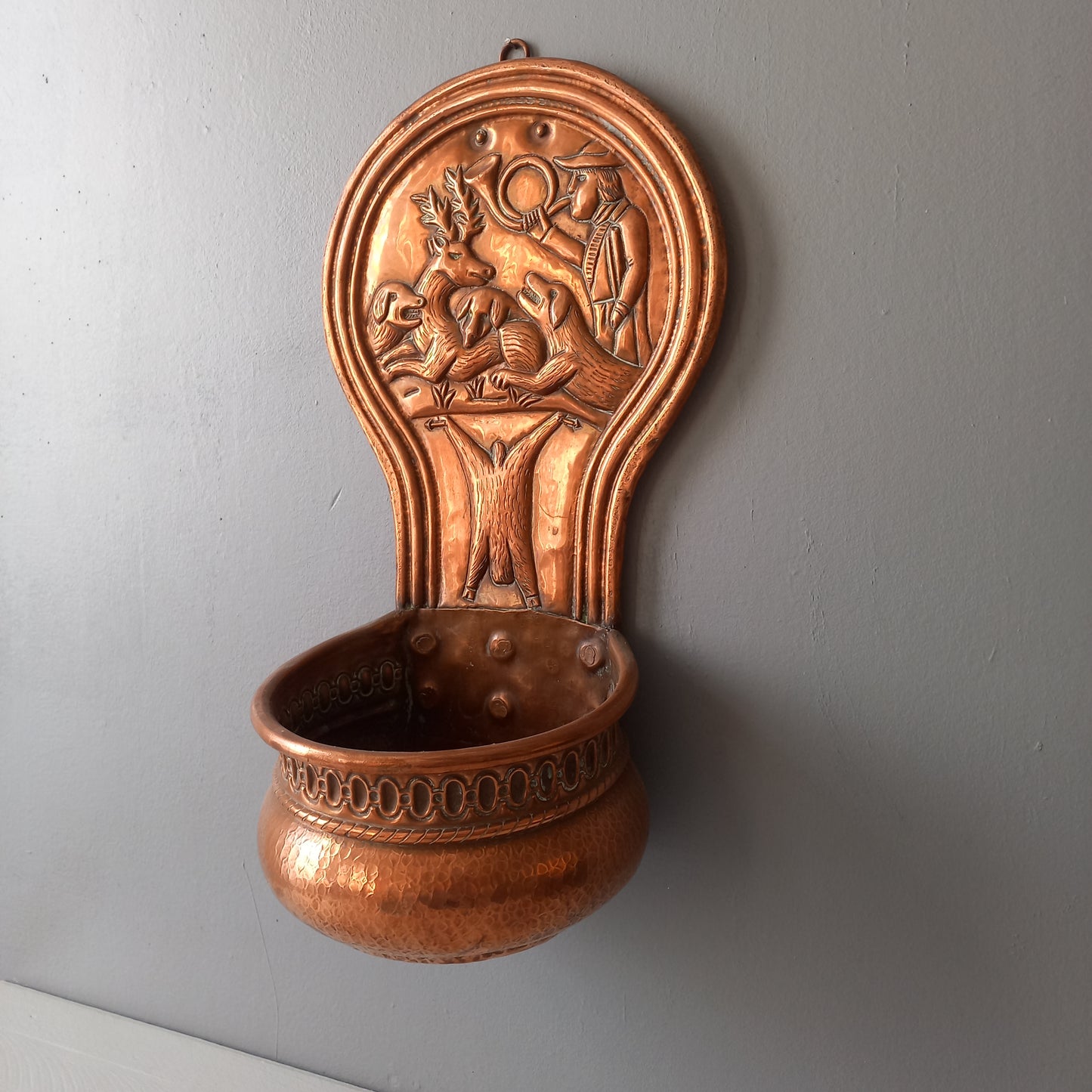 A very handsome copper vintage/antique wall-mounted planter with a hunting scene that I purchased in south west France.
This wonderful rustic piece may at some time have had another purpose, although being a planter seems to suit it just perfectly. There is a hanging hook to the rear, although it can also be displayed sitting on a flat surface as it's depicted in my photos - it's very interesting that we can also see the crude yet charming way this heavy copper planter was constructed by the artisan.