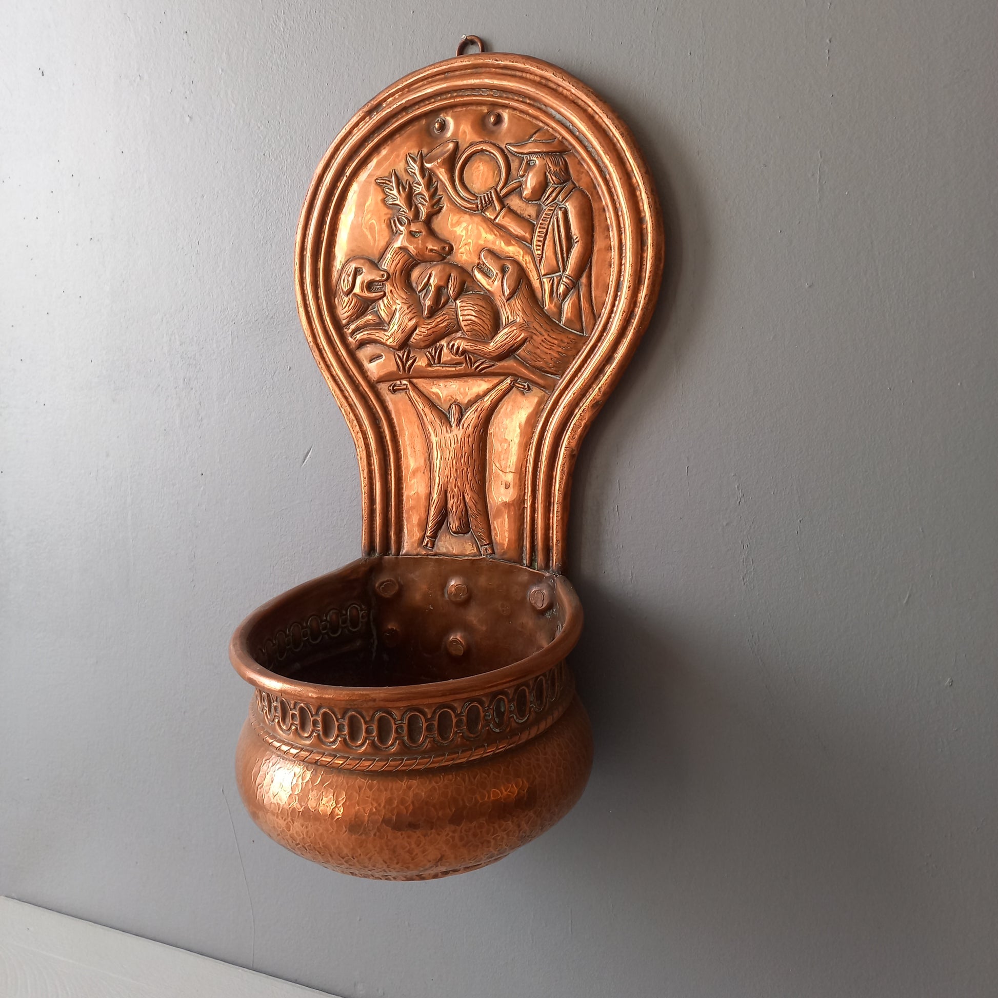 A very handsome copper vintage/antique wall-mounted planter with a hunting scene that I purchased in south west France.
This wonderful rustic piece may at some time have had another purpose, although being a planter seems to suit it just perfectly. There is a hanging hook to the rear, although it can also be displayed sitting on a flat surface as it's depicted in my photos - it's very interesting that we can also see the crude yet charming way this heavy copper planter was constructed by the artisan.
