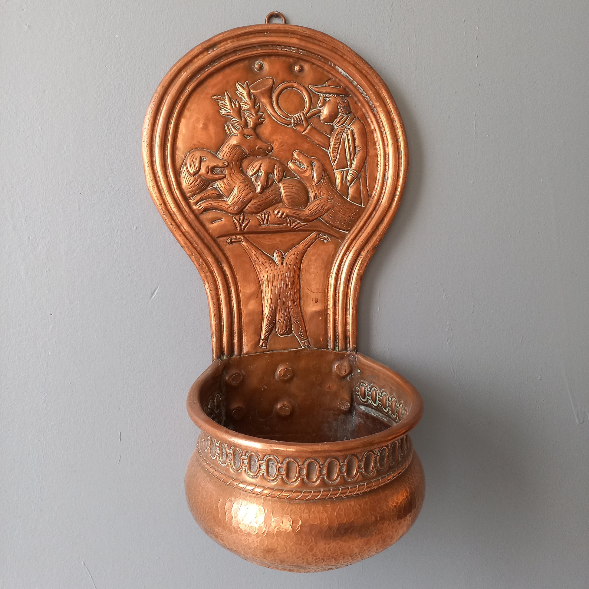 A very handsome copper vintage/antique wall-mounted planter with a hunting scene that I purchased in south west France.
This wonderful rustic piece may at some time have had another purpose, although being a planter seems to suit it just perfectly. There is a hanging hook to the rear, although it can also be displayed sitting on a flat surface as it's depicted in my photos - it's very interesting that we can also see the crude yet charming way this heavy copper planter was constructed by the artisan.