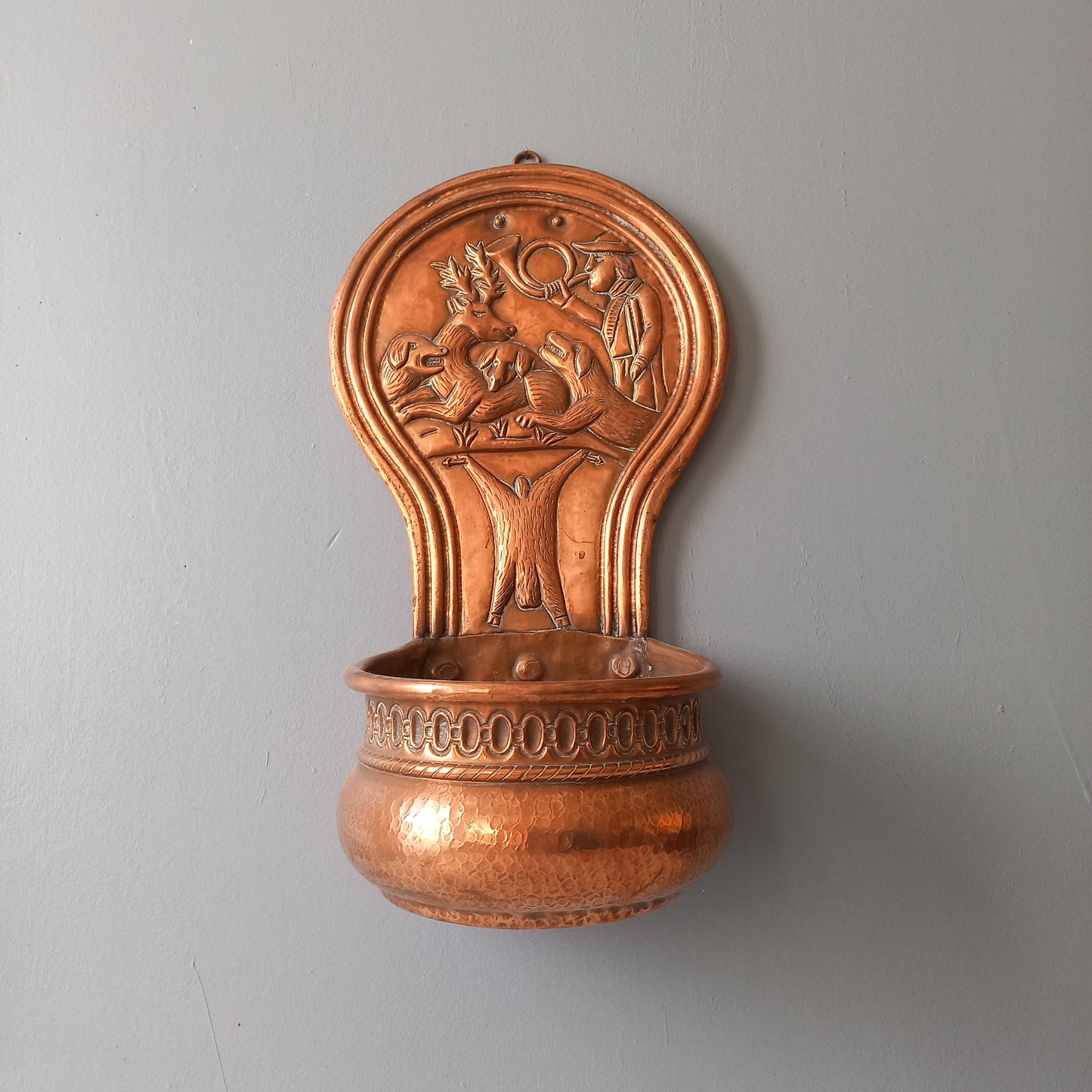 A very handsome copper vintage/antique wall-mounted planter with a hunting scene that I purchased in south west France.
This wonderful rustic piece may at some time have had another purpose, although being a planter seems to suit it just perfectly. There is a hanging hook to the rear, although it can also be displayed sitting on a flat surface as it's depicted in my photos - it's very interesting that we can also see the crude yet charming way this heavy copper planter was constructed by the artisan.