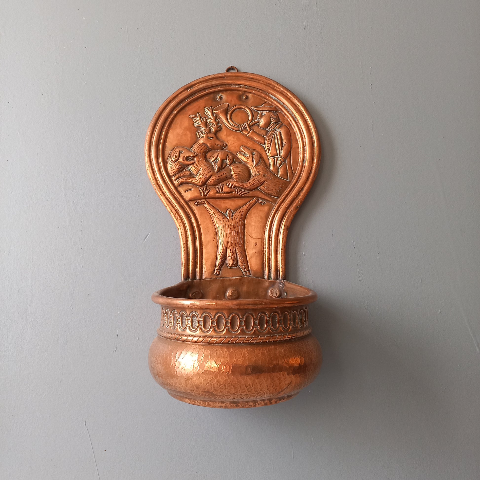 A very handsome copper vintage/antique wall-mounted planter with a hunting scene that I purchased in south west France.
This wonderful rustic piece may at some time have had another purpose, although being a planter seems to suit it just perfectly. There is a hanging hook to the rear, although it can also be displayed sitting on a flat surface as it's depicted in my photos - it's very interesting that we can also see the crude yet charming way this heavy copper planter was constructed by the artisan.