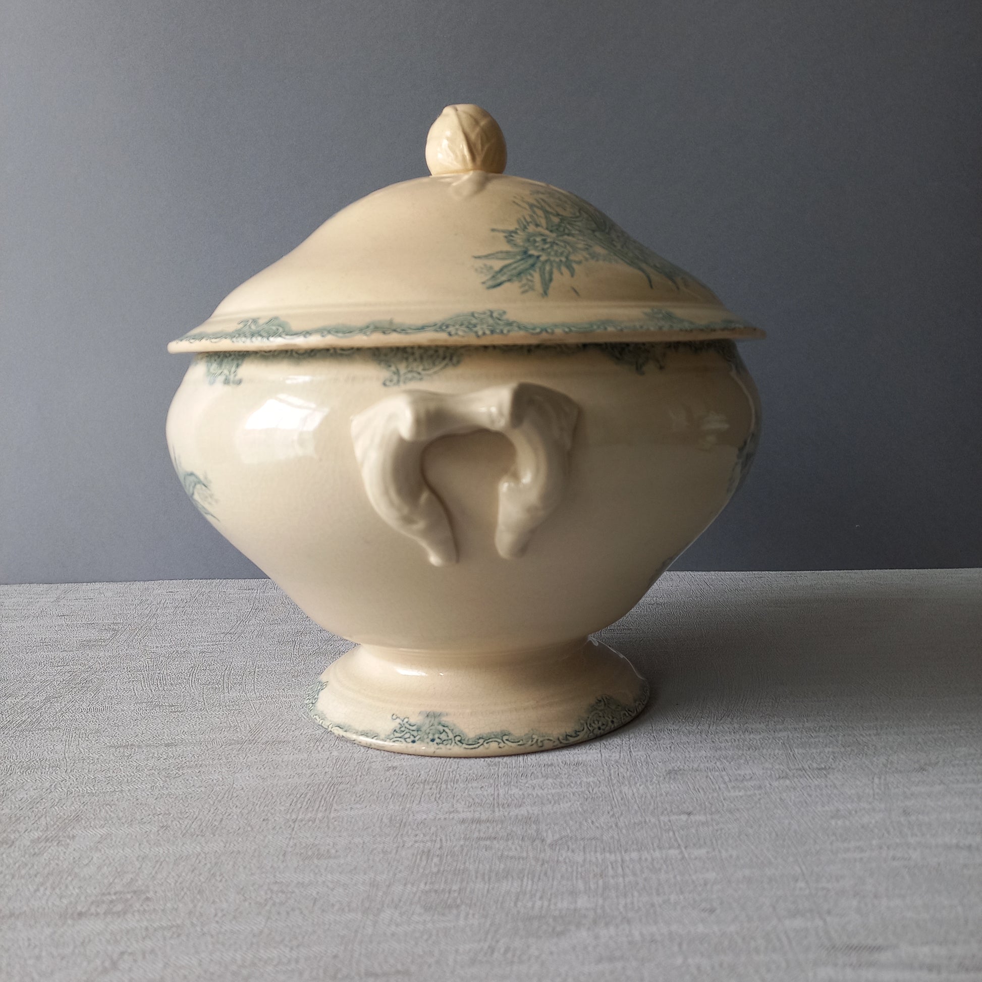 A pretty antique ironstone soup tureen with aged and faded floral transfer pattern in a beautiful shade of blue green or teal. Over time this wonderful old tureen has developed a pleasing faded creamy white finish. In summary, a beautiful piece of authentic antique ironstone from France.