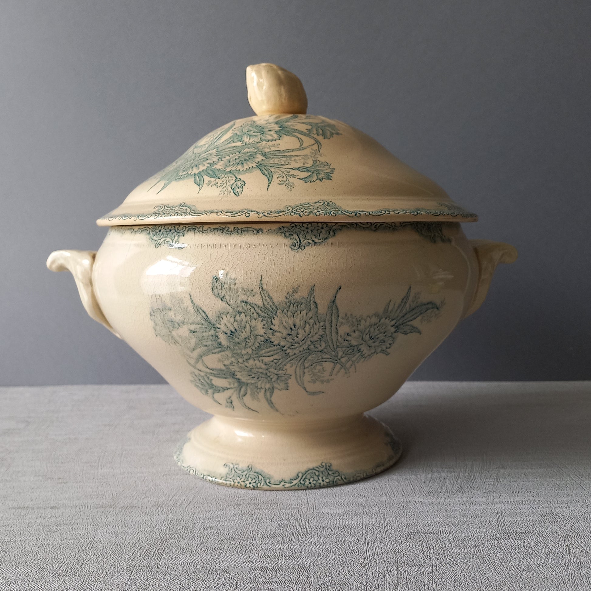 A pretty antique ironstone soup tureen with aged and faded floral transfer pattern in a beautiful shade of blue green or teal. Over time this wonderful old tureen has developed a pleasing faded creamy white finish. In summary, a beautiful piece of authentic antique ironstone from France.