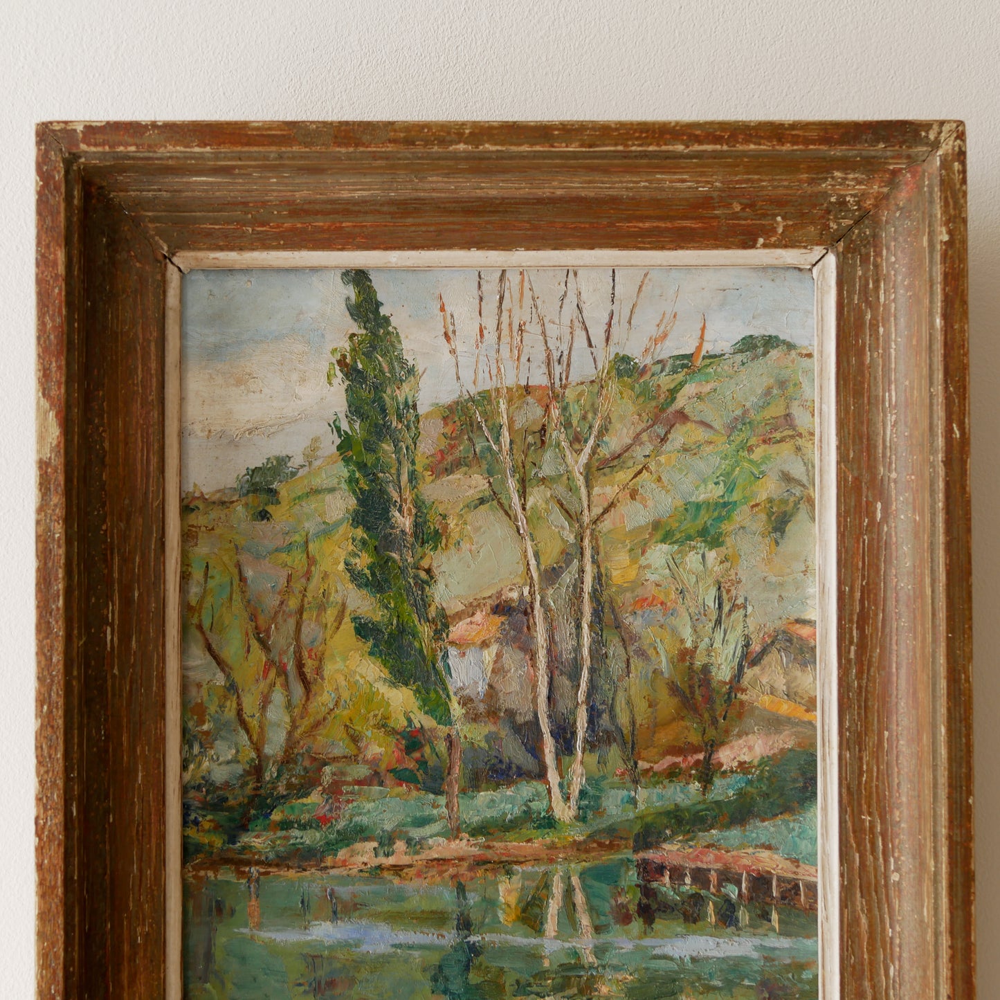 An original vintage landscape oil painting depicting a charming country home in among a wooded area with hills in the background. In the foreground a gentle river reflects the trees in the background.
The painting has been painted by an experienced artist with confident brush strokes - a really wonderful piece of original art.
The painting is presented in an old worn wooden frame which we love and think others will too - it really suits this piece.