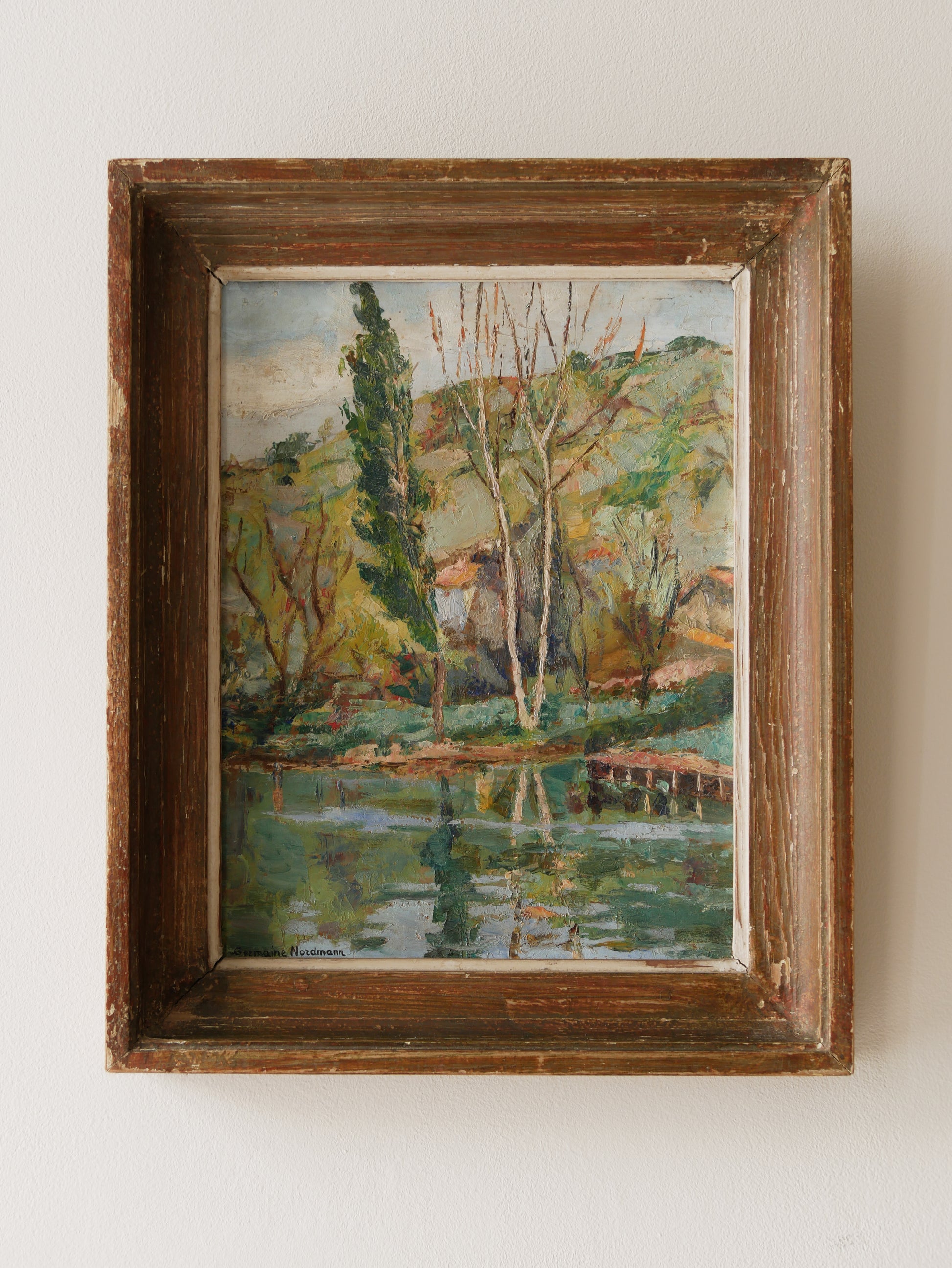 An original vintage landscape oil painting depicting a charming country home in among a wooded area with hills in the background. In the foreground a gentle river reflects the trees in the background.
The painting has been painted by an experienced artist with confident brush strokes - a really wonderful piece of original art.
The painting is presented in an old worn wooden frame which we love and think others will too - it really suits this piece.