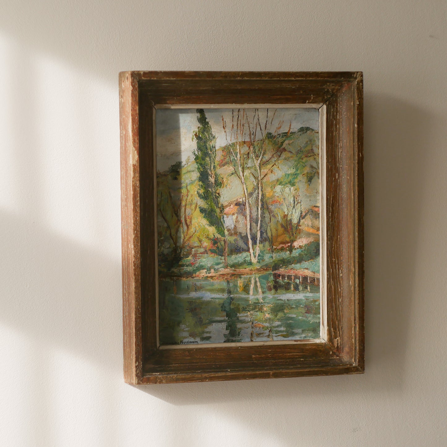 An original vintage landscape oil painting depicting a charming country home in among a wooded area with hills in the background. In the foreground a gentle river reflects the trees in the background.
The painting has been painted by an experienced artist with confident brush strokes - a really wonderful piece of original art.
The painting is presented in an old worn wooden frame which we love and think others will too - it really suits this piece.