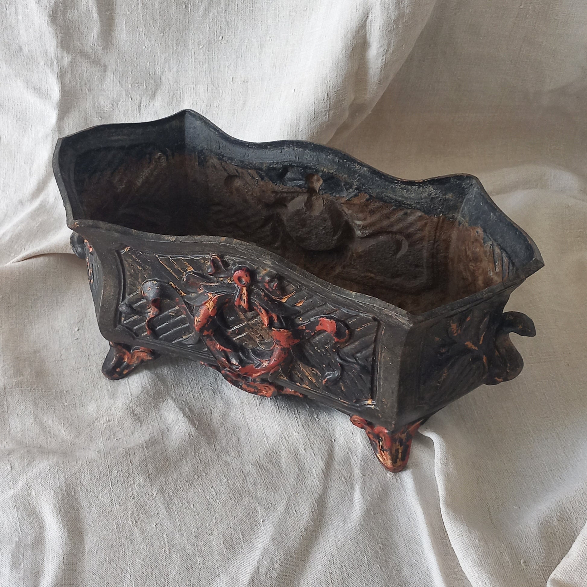 A stunning French antique decorative cast iron planter with patina of age suitable for both interior and exterior use - we rarely come across them these days so this was an exciting find.
The planter is in a striking and wonderfully aged black colour with gold coloured detailing in relief - there's some great paint chipping off areas of the gold paint showing small areas of red beneath, and also chipping from the black paint showing rusty patina, all of which add to the antique character of this beautiful