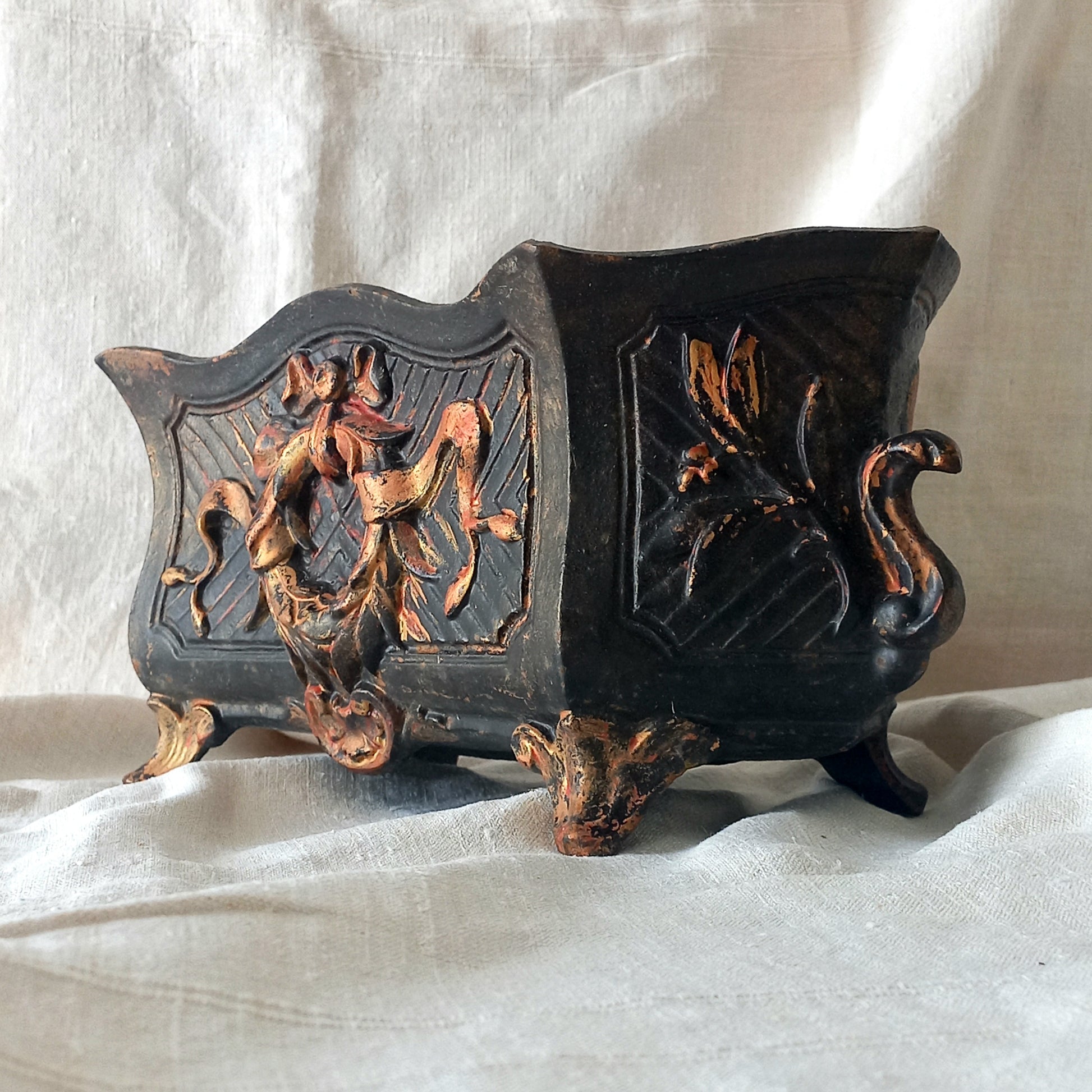 A stunning French antique decorative cast iron planter with patina of age suitable for both interior and exterior use - we rarely come across them these days so this was an exciting find.
The planter is in a striking and wonderfully aged black colour with gold coloured detailing in relief - there's some great paint chipping off areas of the gold paint showing small areas of red beneath, and also chipping from the black paint showing rusty patina, all of which add to the antique character of this beautiful