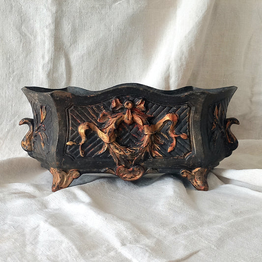 A stunning French antique decorative cast iron planter with patina of age suitable for both interior and exterior use - we rarely come across them these days so this was an exciting find.
The planter is in a striking and wonderfully aged black colour with gold coloured detailing in relief - there's some great paint chipping off areas of the gold paint showing small areas of red beneath, and also chipping from the black paint showing rusty patina, all of which add to the antique character of this beautiful
