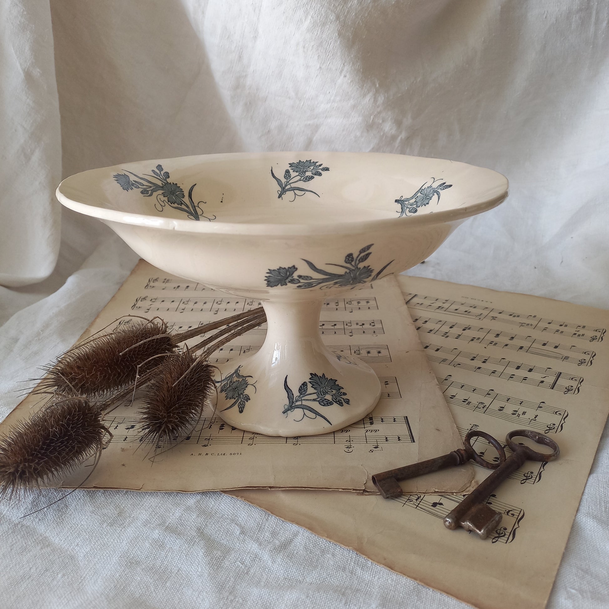 A beautiful antique compote or footed bowl by French manufacturer Longchamp. The main colour is a warm cream/white with blue floral transfer ware pattern.