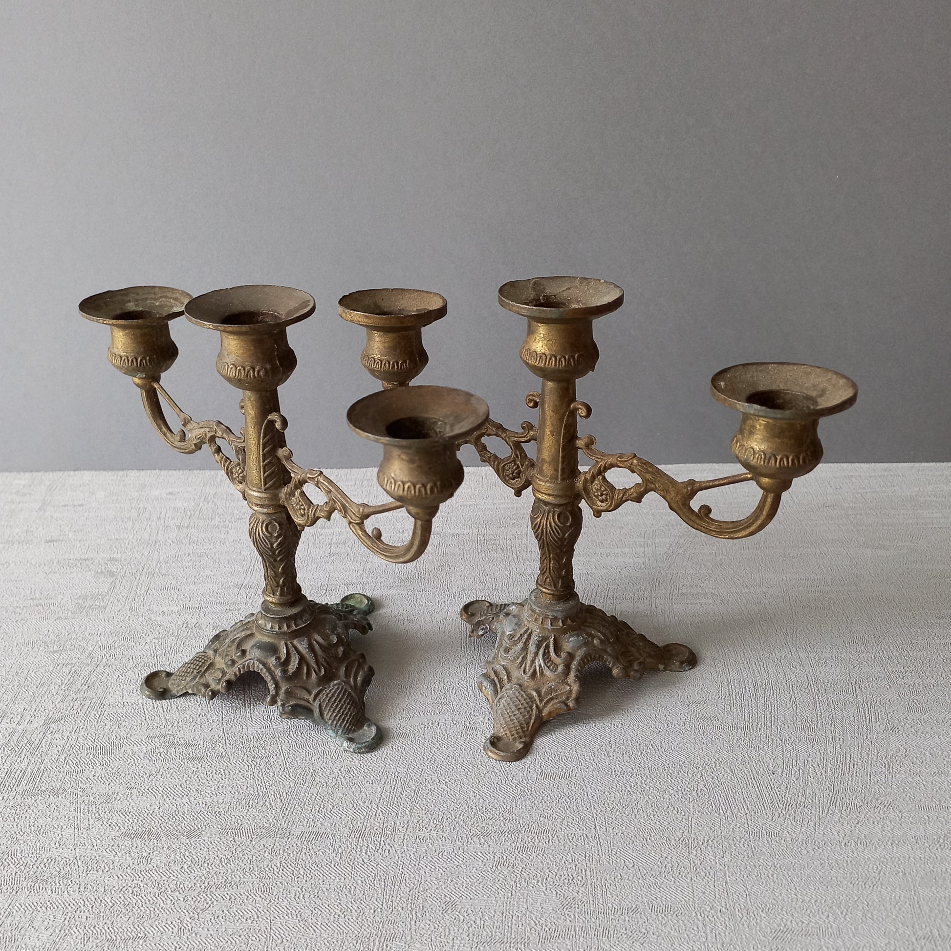 A pair of small vintage antique metal candelabras. This pair of decorative candle stick holders will give that touch of French shabby chic to any interior.