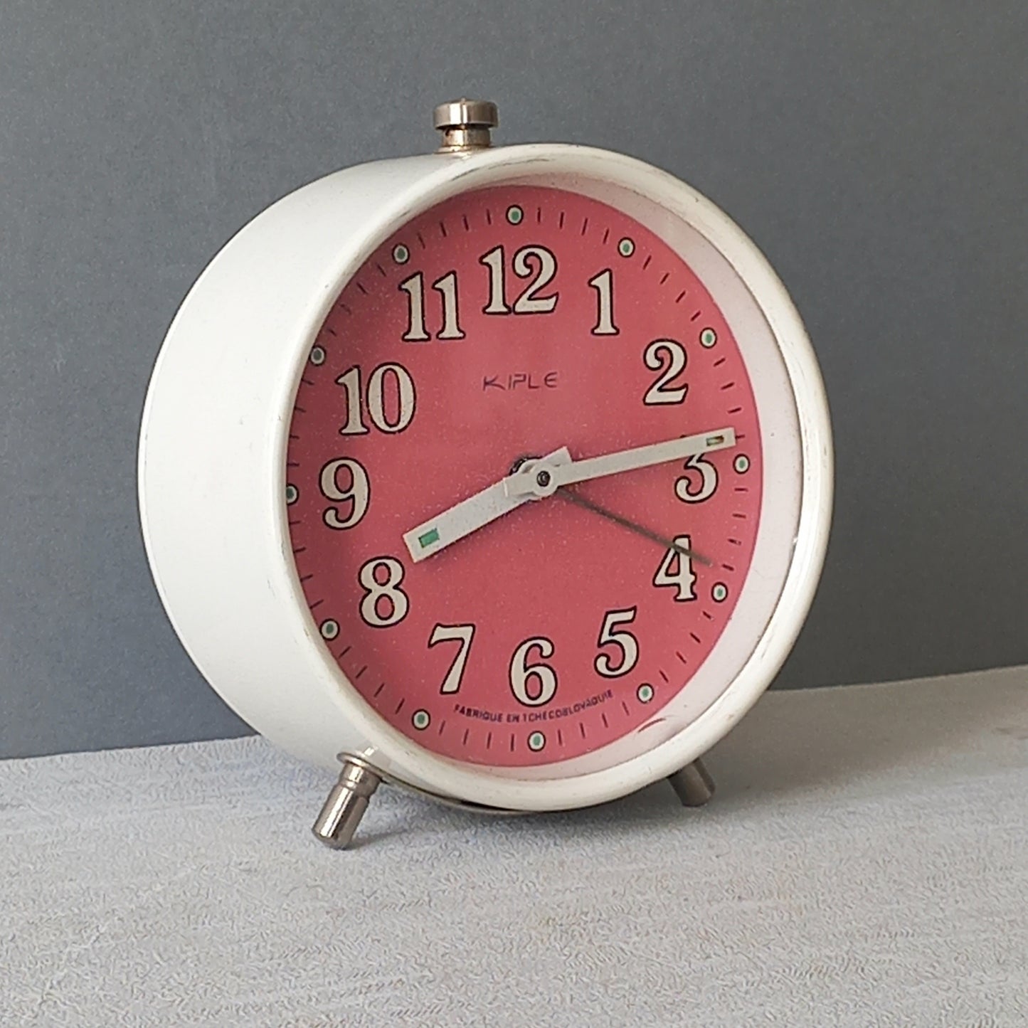 A wonderful vintage alarm clock in an eye-catching white and pink color scheme. This old clock is in working condition including the alarm and has a nice soothing ticking sound too. A great piece of European history from the former country of Czechoslovakia.
