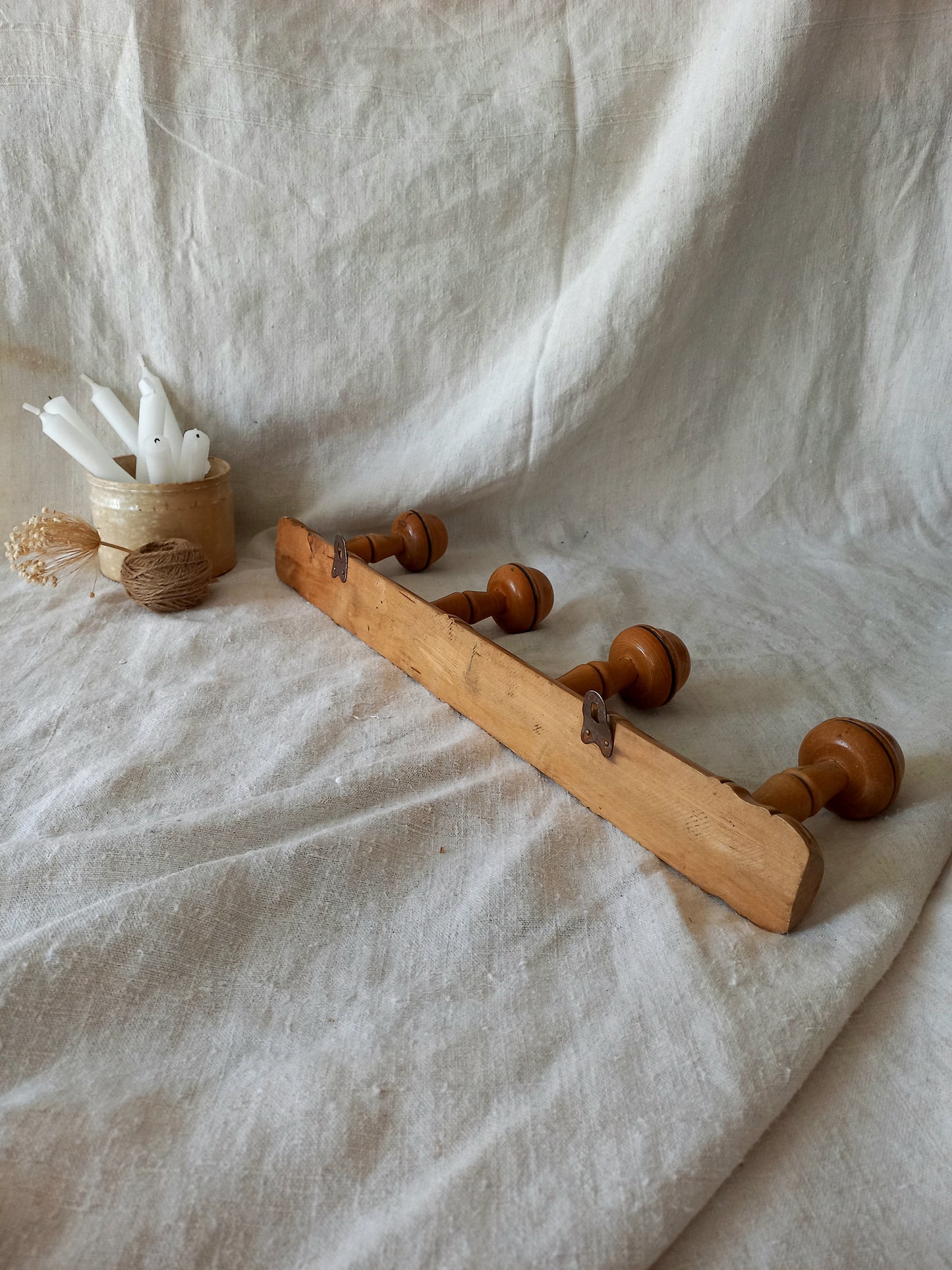 Rear of 4 peg faux bamboo wooden coat rack on a textured white fabric background
