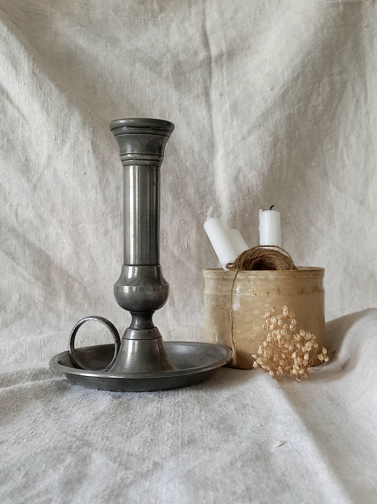 pewter candlestick holder on a textured white fabric background