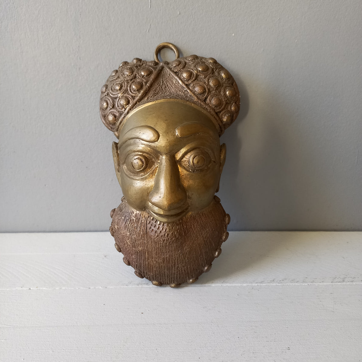 An interesting little vintage tribal mask I purchased in France. It's a heavy, quality piece made from a brass-coated metal and would look great in an ethic mask collection or as a stand alone piece of wall decor.