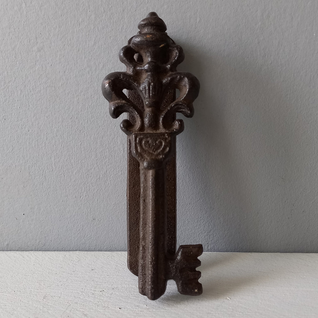 Decorative metal key-shaped object on a plain background