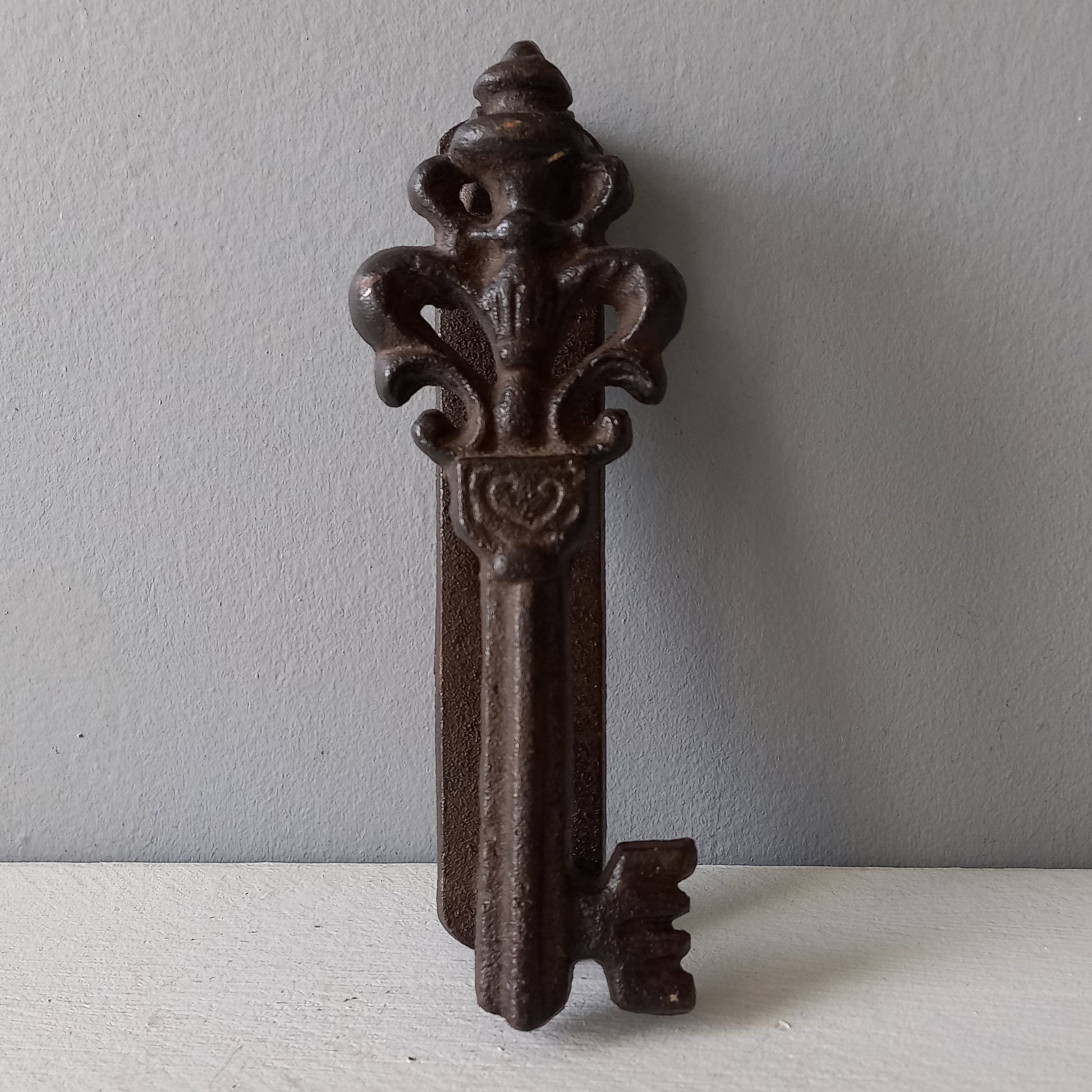 Decorative metal key-shaped object on a plain background