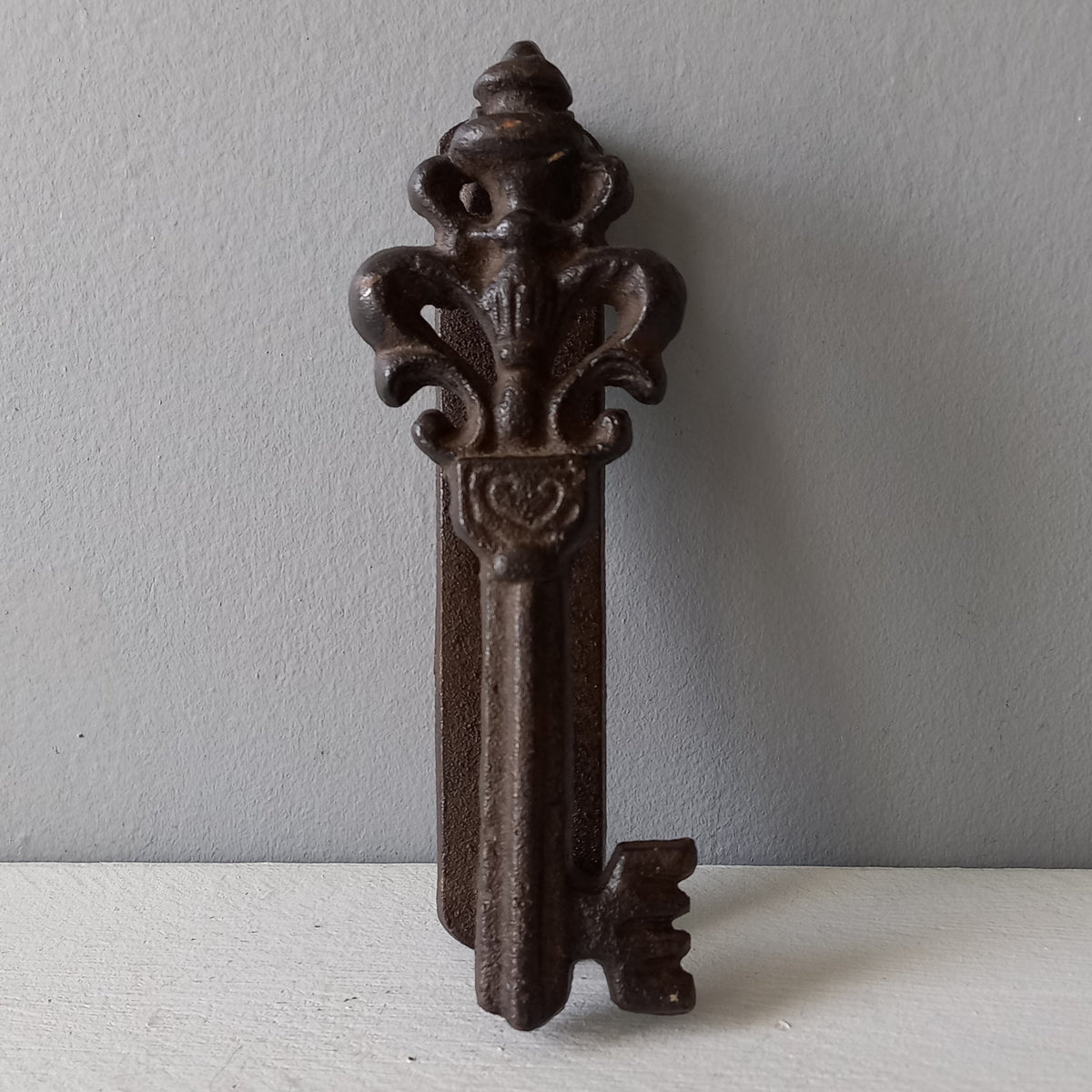 Decorative metal key-shaped object on a plain background
