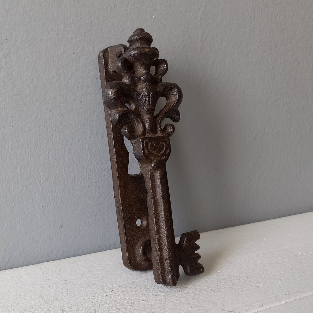 Decorative metal key-shaped object on a light gray surface