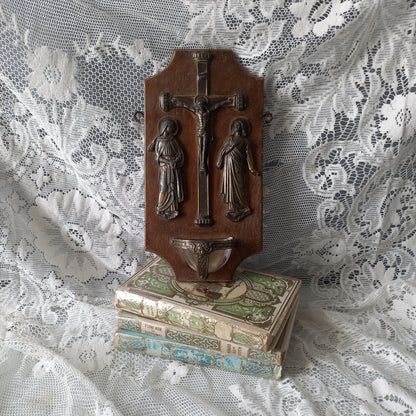 Wall-mounted vintage/antique religious wall decor with metal crucifix and religious figures, and a glass Holy Water font mounted to a wooden base. A great piece of original religious decor from France.