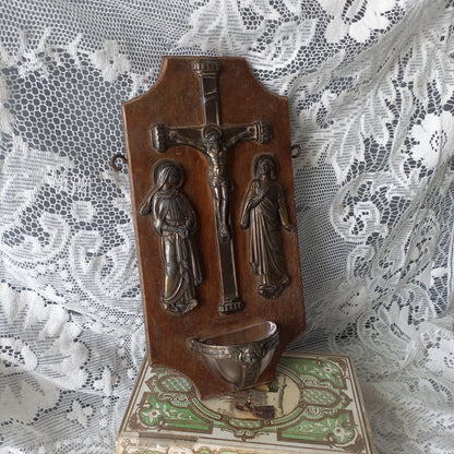 Wall-mounted vintage/antique religious wall decor with metal crucifix and religious figures, and a glass Holy Water font mounted to a wooden base. A great piece of original religious decor from France.