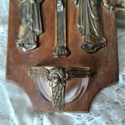 Wall-mounted vintage/antique religious wall decor with metal crucifix and religious figures, and a glass Holy Water font mounted to a wooden base. A great piece of original religious decor from France.