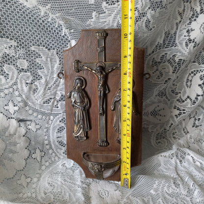 Wall-mounted vintage/antique religious wall decor with metal crucifix and religious figures, and a glass Holy Water font mounted to a wooden base. A great piece of original religious decor from France.