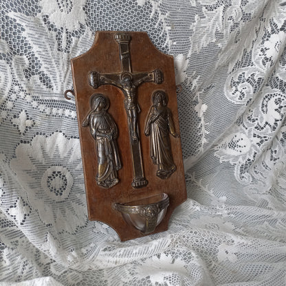 Wall-mounted vintage/antique religious wall decor with metal crucifix and religious figures, and a glass Holy Water font mounted to a wooden base. A great piece of original religious decor from France.