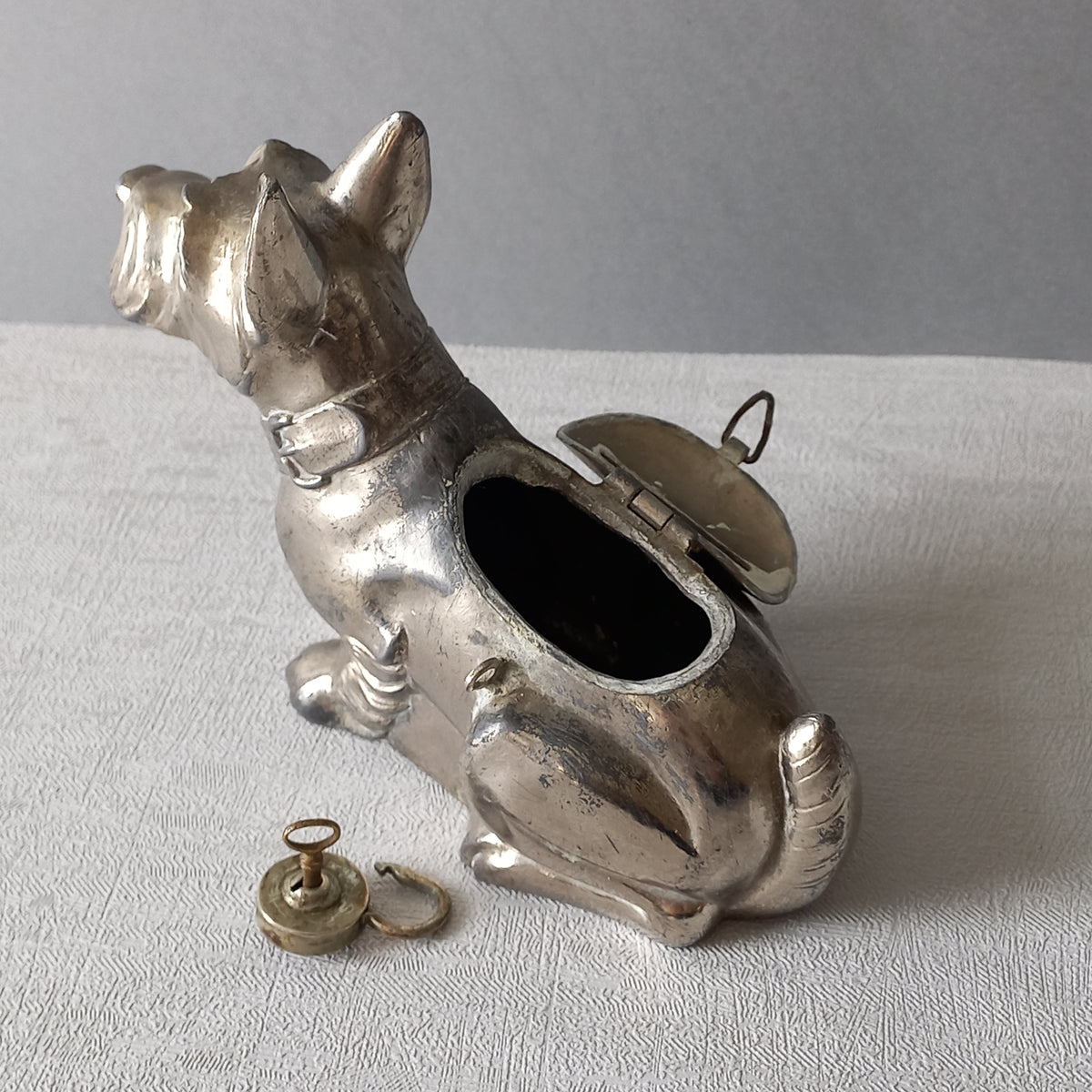 A fabulous French art deco metal terrier dog money box/coin storage box complete with a little padlock and key which still work. 

This unique piece of history was purchased in south west France and we can only imagine who once owned it and what they might have saved their coins to buy.