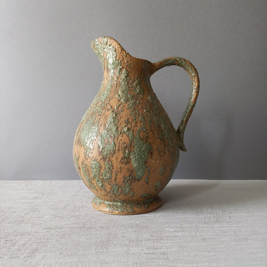 Vintage pottery pitcher or jug with earthy tones and green pattern in relief