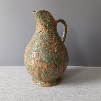 Vintage pottery pitcher or jug with earthy tones and green pattern in relief