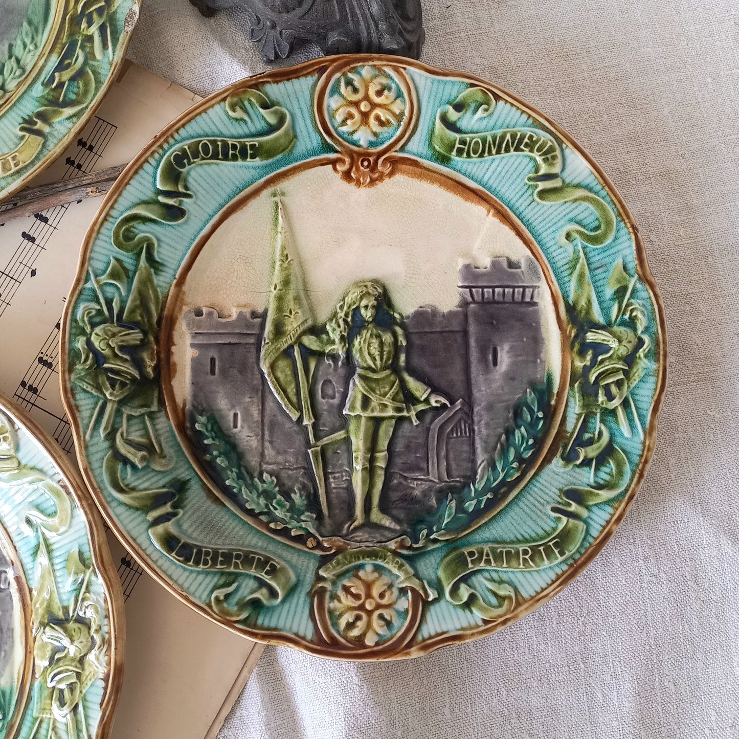 Decorative ceramic plate with a central figure and castle design, surrounded by green decorative elements.