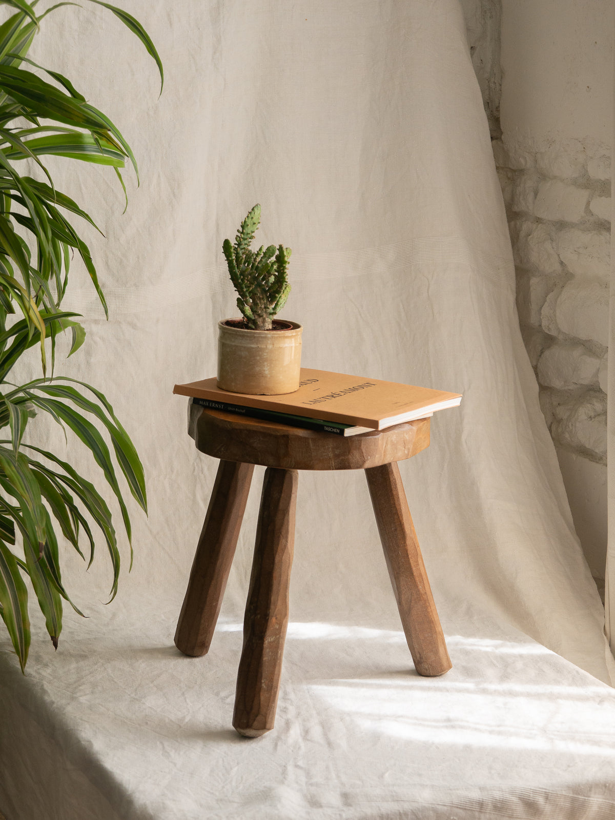 A French vintage chunky three legged wooden stool, a rustic piece with a lovely thick wooden seat that shows the natural pattern of the wood beautifully.