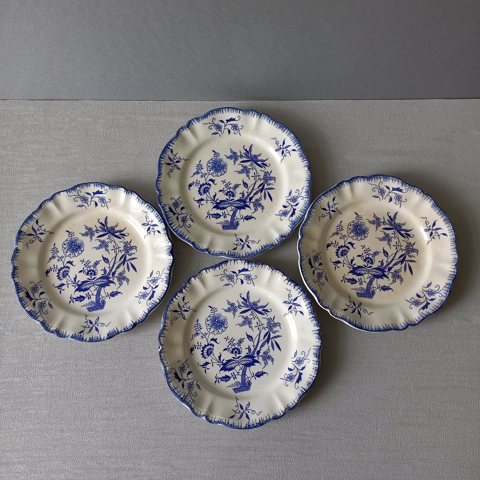 A stunning set of 4 small antique white ironstone plates with blue floral patterns from France.