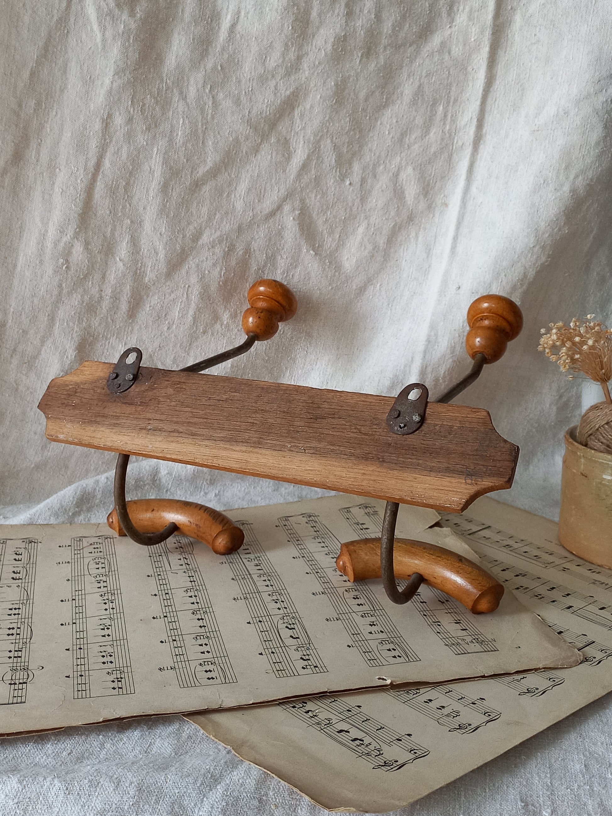 Rear of French vintage coat and hat rack with 2 metal hooks, each hook having wooden pegs for a hat and a coat.

