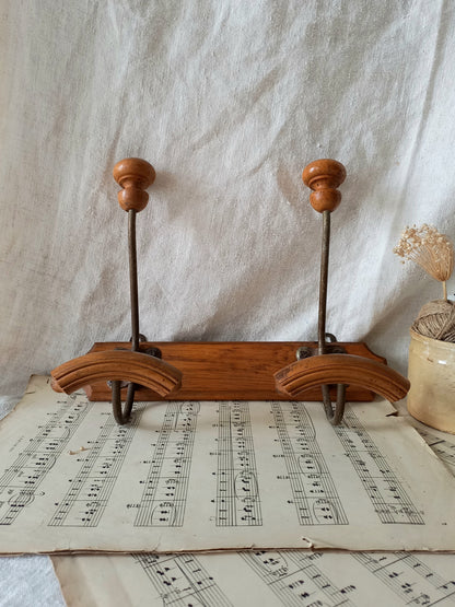 French vintage coat and hat rack with 2 metal hooks, each hook having wooden pegs for a hat and a coat.

